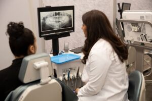 What is surgical orthodontics? 3 Dentist showing patient x-ray, representing what is surgical orthodontics?