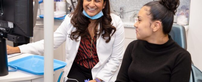 Extraction therapy vs. Non-extraction therapy 5 Dr. Parikh looking at computer screen with patient