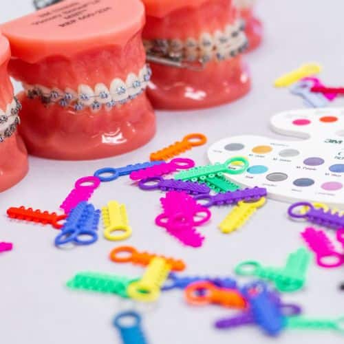 New patients 5 Typodonts wearing braces and colorful bands flat lay