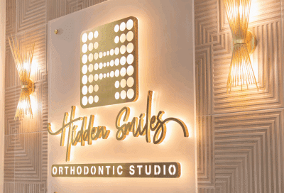 Exciting news: hidden smiles orthodontic studio is moving to a new office! 9 A sign on a wall with hidden smiles orthodontic studio logo on it, representing their new office location