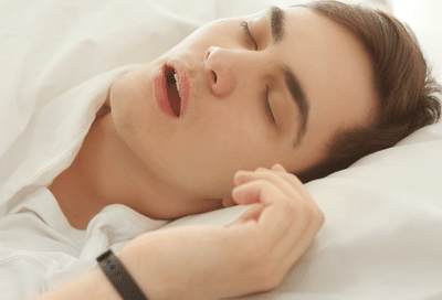 The link between orthodontics and sleep apnea: how proper alignment can improve sleep quality 4 Man suffering from sleep apnea while asleep in bed, representing orthodontics and sleep apnea
