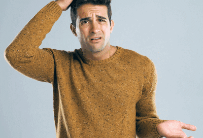 How long to wear a retainer? 3 Man holding one hand out and the other on his head, looking confused, representing how long to wear a retainer