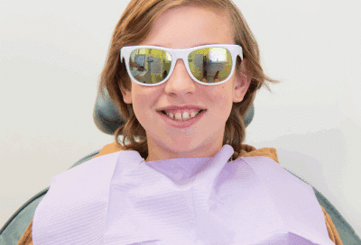 Lightforce clear braces: the benefits of 3d-printed, customized braces 11 A boy wearing sunglasses and a purple dental towel, representing lightforce clear braces